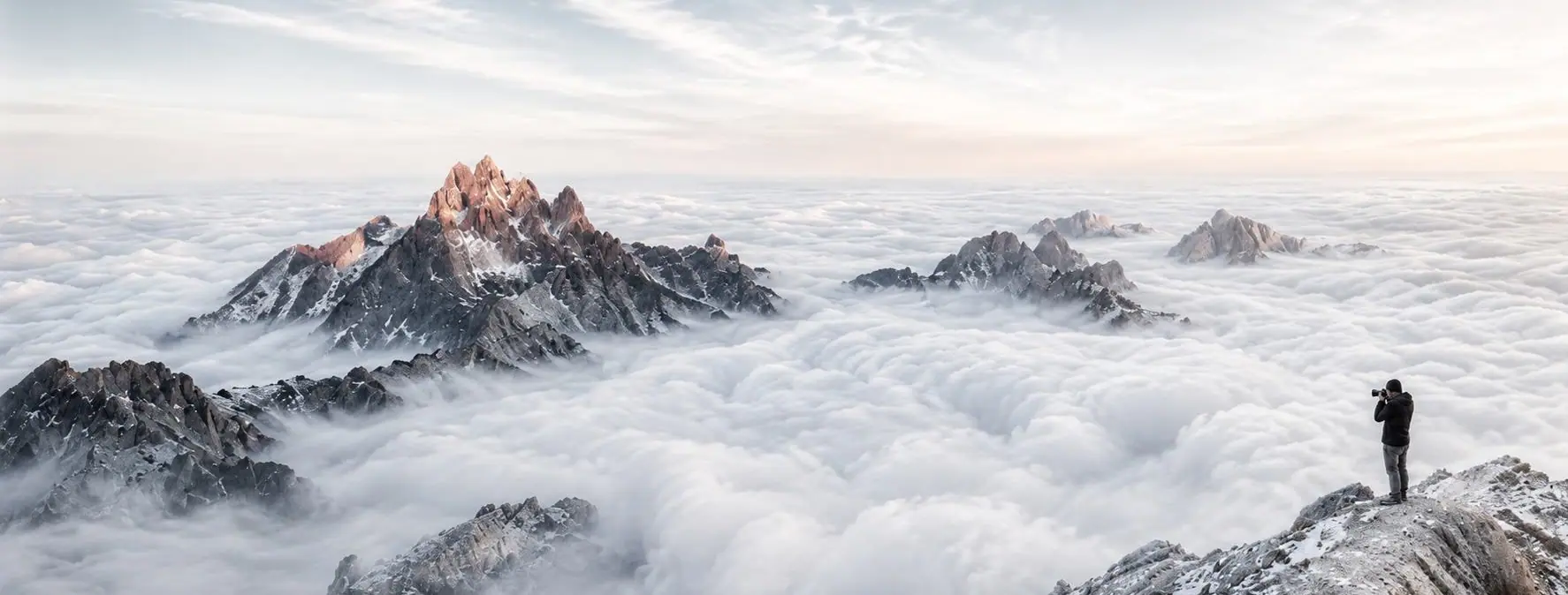 Fotógrafo en la cima de una montaña sobre un mar de nubes